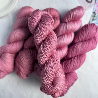 Pink yarn skeins on a light surface with a blurred background