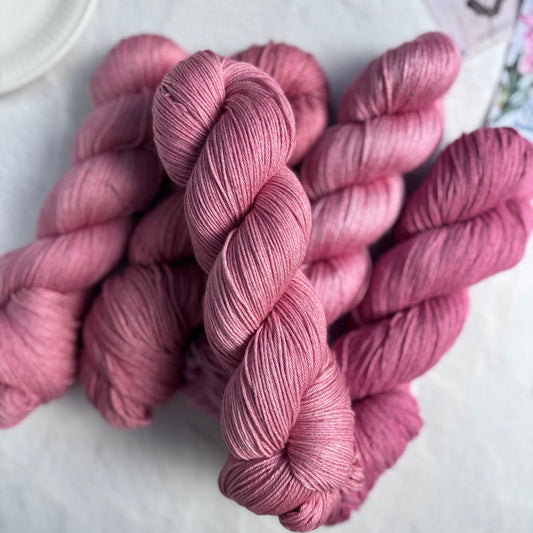 Pink yarn skeins on a light surface with a blurred background
