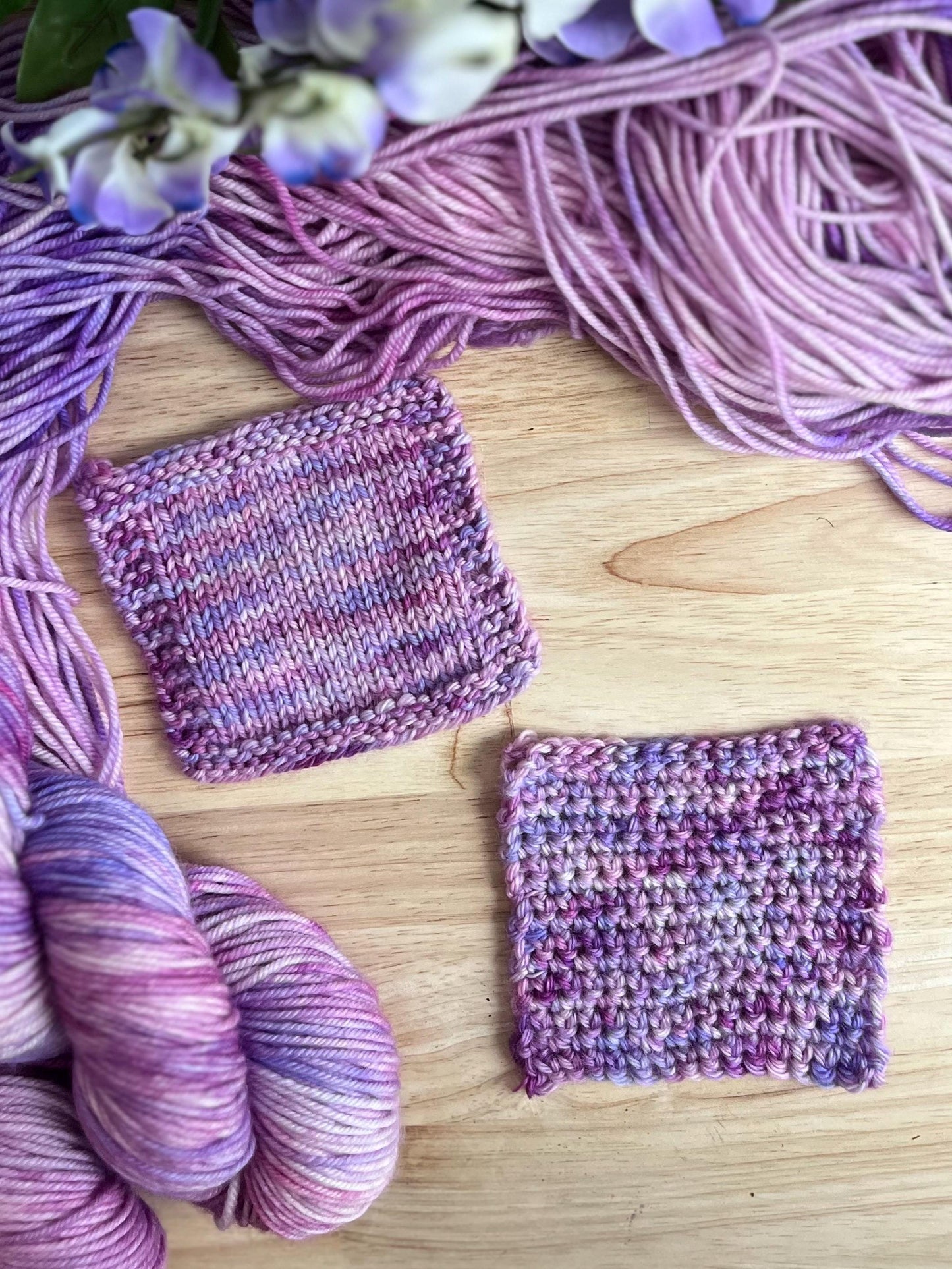Knit and crochet swatches of hand dyed pink and purple merino wool yarn.