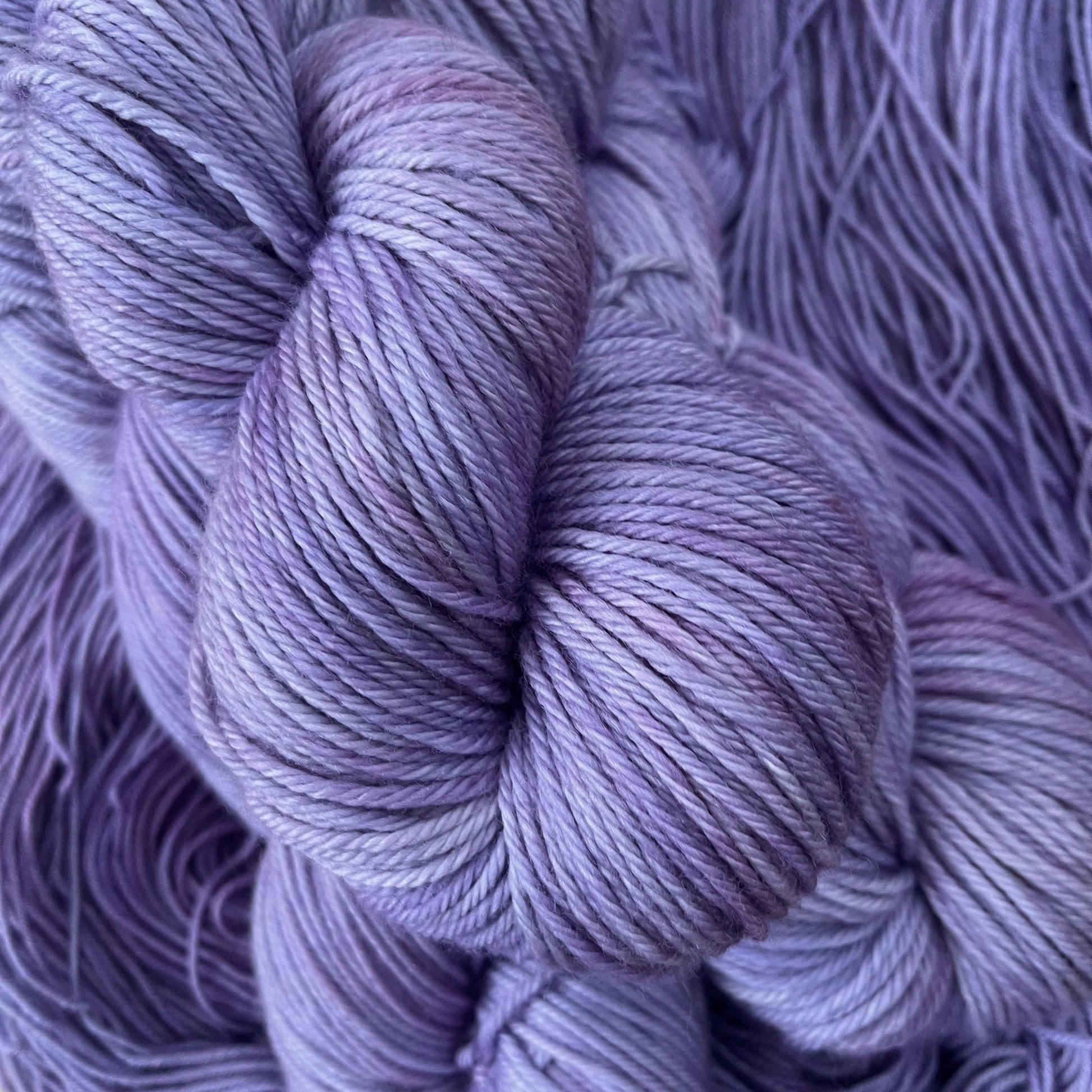 Skeins of hand dyed soft purple yarn.