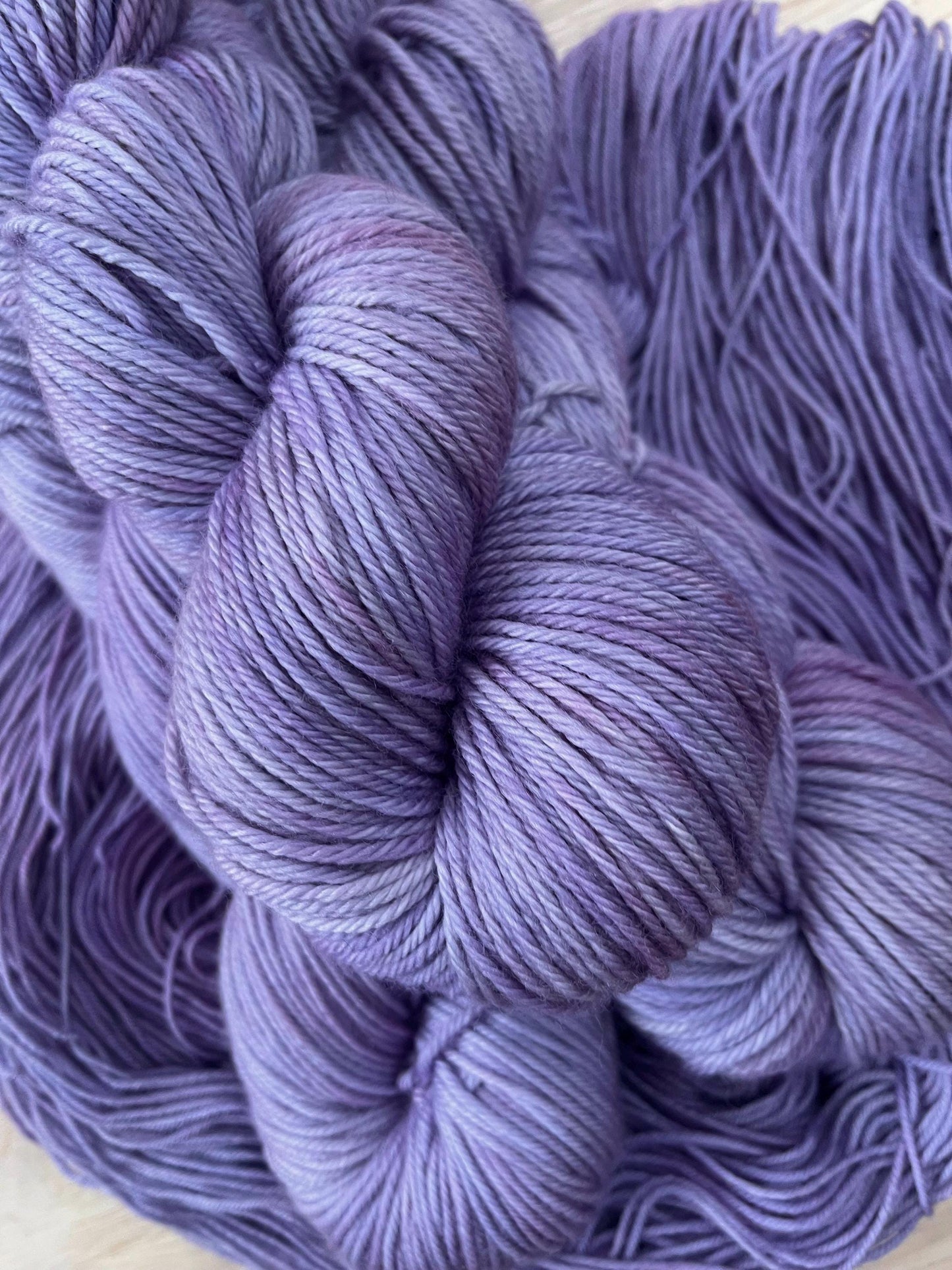 A skein of worsted weight light purple hand dyed wool yarn.
